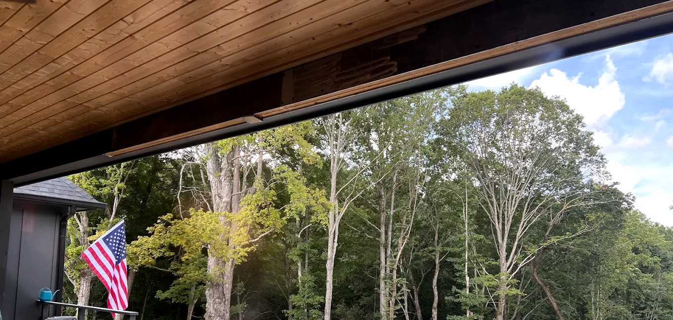 A steel beam carrying a covered porch over an open wooded view